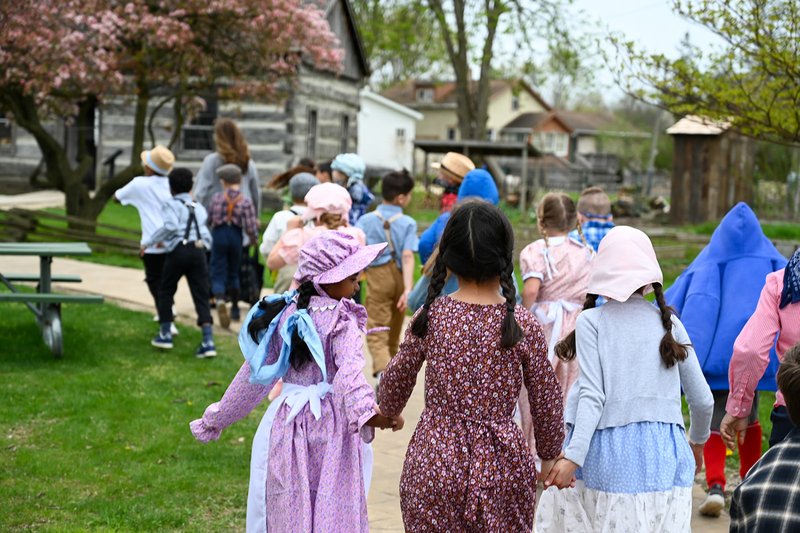 School group dressed up and walking towards the Log Cabin.